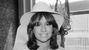 A black and white photo of a woman posing for a picture wearing a hat.